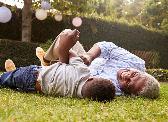 Grandfather and grandson play lying on grass